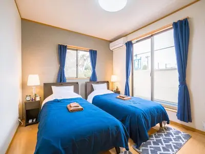 two beds in a room with blue curtains and a window at Katsushika Takasago House in Tokyo