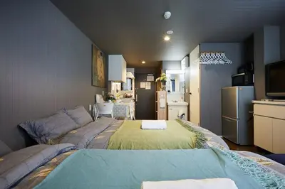 a room with two beds and a kitchen with a refrigerator at Akabane TK Building 101 in Tokyo