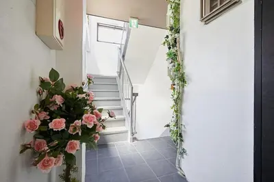 a hallway with flowers on the wall and stairs at Akabane TK Building 101 in Tokyo