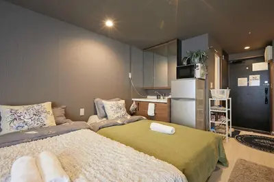 a bedroom with a bed and a kitchen with a refrigerator at Akabane TK Building 102 in Tokyo