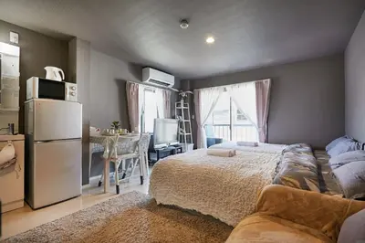 a bedroom with a bed and a refrigerator and a table at Akabane TK Building 201 in Tokyo