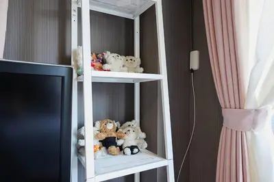 a white shelf filled with stuffed animals next to a tv at Akabane TK Building 201 in Tokyo
