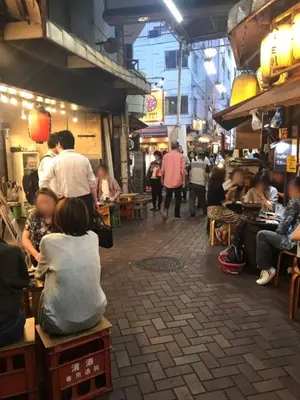 a group of people sitting in a street market at Akabane TK Building 302 in Tokyo