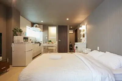 a bedroom with a large white bed and a kitchen at Akabane TK Building 303 in Tokyo