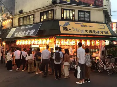 a group of people standing in front of a food stand at Kamiya TK Building 203 in Tokyo
