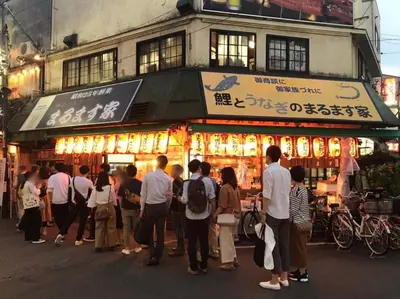 a group of people standing in front of a food stand at Kamiya TK Building 301 in Tokyo