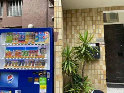 a vending machine filled with drinks next to a building at Takemura Building 301 in Tokyo