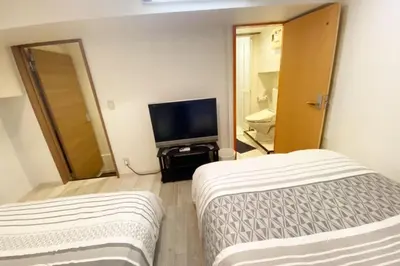 a room with two beds and a flat screen tv at Takemura Building 104 in Tokyo