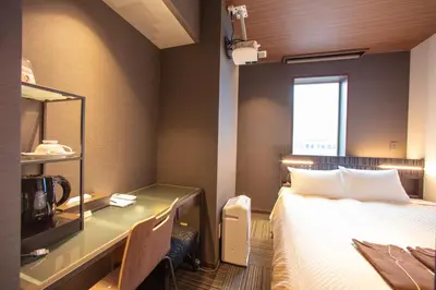 a hotel room with a bed and a desk with a microwave at JHotelTokyoGEO in Tokyo