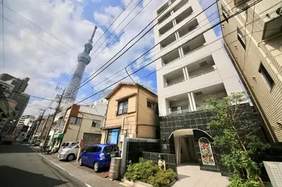 a blue car parked in front of a building with a tv tower at NorthRiverSKY in Tokyo