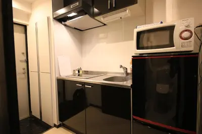 a kitchen with a sink and a microwave on top of a refrigerator at NorthRiverSKY in Tokyo