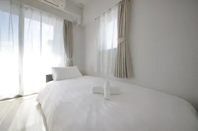a white bedroom with a white bed with a cross on it at NorthRiverSKY in Tokyo
