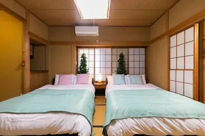 two beds in a room with windows at Shinjuku Japanese-style two storey house in Tokyo