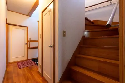 a hallway with stairs and a door with a rug at Shinjuku Japanese-style two storey house in Tokyo