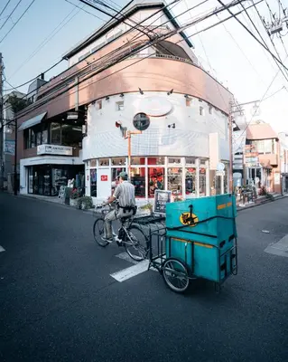 a man riding a bike in front of a building at illi Sun Shimokitazawa in Tokyo