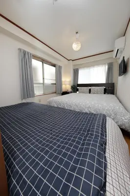 a bedroom with two beds and two windows at Ikebukuro Apartment by Tranova in Tokyo