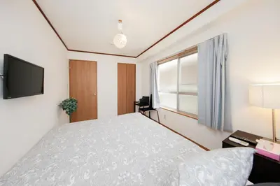 a bedroom with a bed and a tv and a window at Ikebukuro Apartment by Tranova in Tokyo