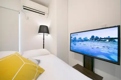 a bedroom with a tv on the wall next to a bed at Real Kinshi in Tokyo