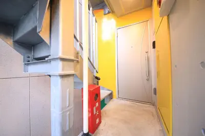 a small room with a door and a yellow wall at Real Kinshi in Tokyo