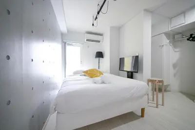 a white bedroom with a bed and a tv at Real Kinshi in Tokyo