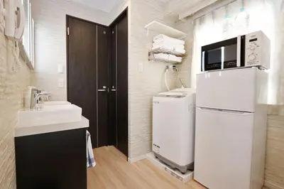 a small bathroom with a refrigerator and a sink at Petit Grande Miyabi in Tokyo