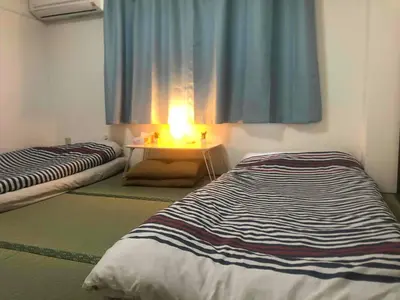 a room with two beds and a table with a light at Cozy room in Itabashi in Tokyo