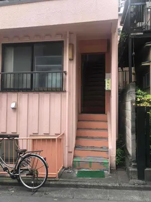 a bike parked in front of a pink house at Cozy room in Itabashi in Tokyo