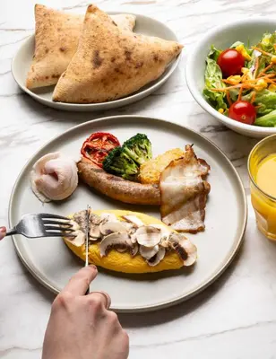 a table with plates of food and a person holding a fork at NOHGA HOTEL AKIHABARA TOKYO in Tokyo