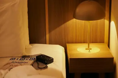 a lamp on a table next to a bed with a book at NOHGA HOTEL AKIHABARA TOKYO in Tokyo