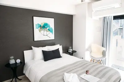 a bedroom with a white bed and a gray wall at Dash Living Nihonbashi in Tokyo