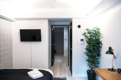 a bedroom with a bed and a tv on a wall at Dash Living Nihonbashi in Tokyo