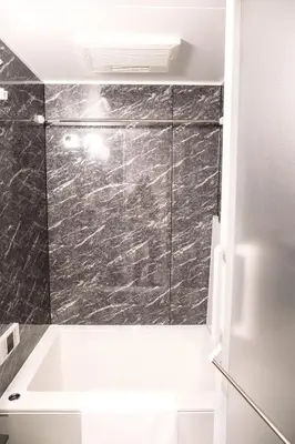 a bathroom with a bath tub with a marble wall at Dash Living Nihonbashi in Tokyo