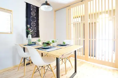a dining room with a wooden table and white chairs at SAKURANOMA in Tokyo