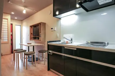 a kitchen with black cabinets and a table with stools at YADOYA Iriyaan in Tokyo