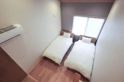 a small bedroom with two beds and a window at YADOYA Iriyaan in Tokyo