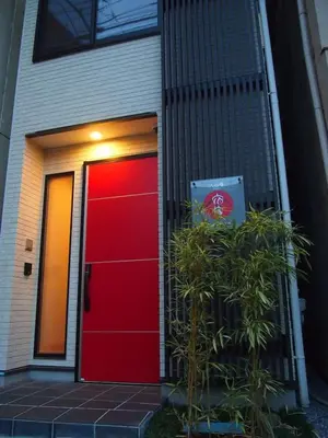 a red door of a house with a plant at YADOYA Iriyaan in Tokyo