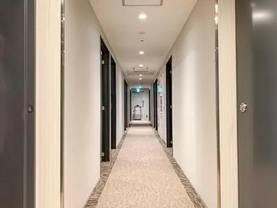 a hallway with white walls and a long aisle at HOTEL LiVEMAX Shinjuku Kabukicho in Tokyo