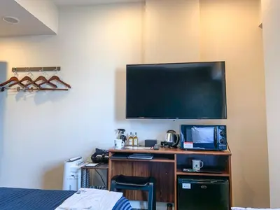 a room with a desk with a television on a wall at HOTEL LiVEMAX Shinjuku Kabukicho in Tokyo