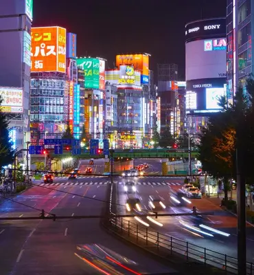 a busy city street at night with cars and buildings at Kimpton Shinjuku Tokyo by IHG in Tokyo