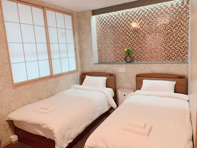 two beds in a room with two windows at Allcomein Hotel Akihabara in Tokyo
