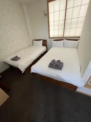 two beds in a room with white sheets and towels on them at Allcomein Hotel Akihabara in Tokyo