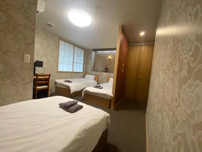 a hotel room with two beds and a chair at Allcomein Hotel Akihabara in Tokyo