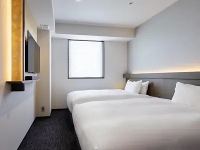 a hotel room with two beds and a television at Agora Tokyo Ginza in Tokyo