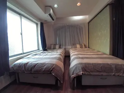 two beds in a room with two windows at Miki Hall Akabane in Tokyo