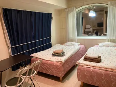 a room with two beds and a table and a mirror at Miki Hall Akabane in Tokyo