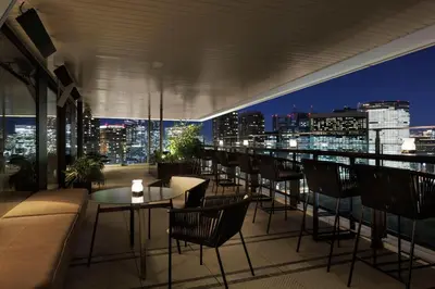 a rooftop bar with chairs and tables and a city skyline at mesm Tokyo, Autograph Collection in Tokyo