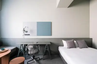a bedroom with a bed and a desk with a computer at KAIKA Tokyo by THE SHARE HOTELS in Tokyo