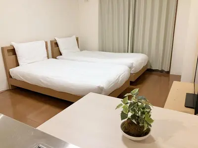 two beds in a hotel room with a potted plant at CIEL BLEU in Tokyo