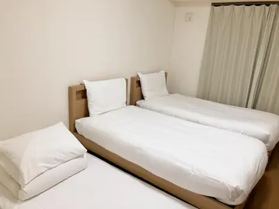 two beds in a room with white sheets and pillows at CIEL BLEU in Tokyo