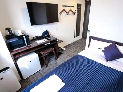 a hotel room with a bed and a desk with a television at HOTEL LiVEMAX Tokyo Kanda EAST in Tokyo